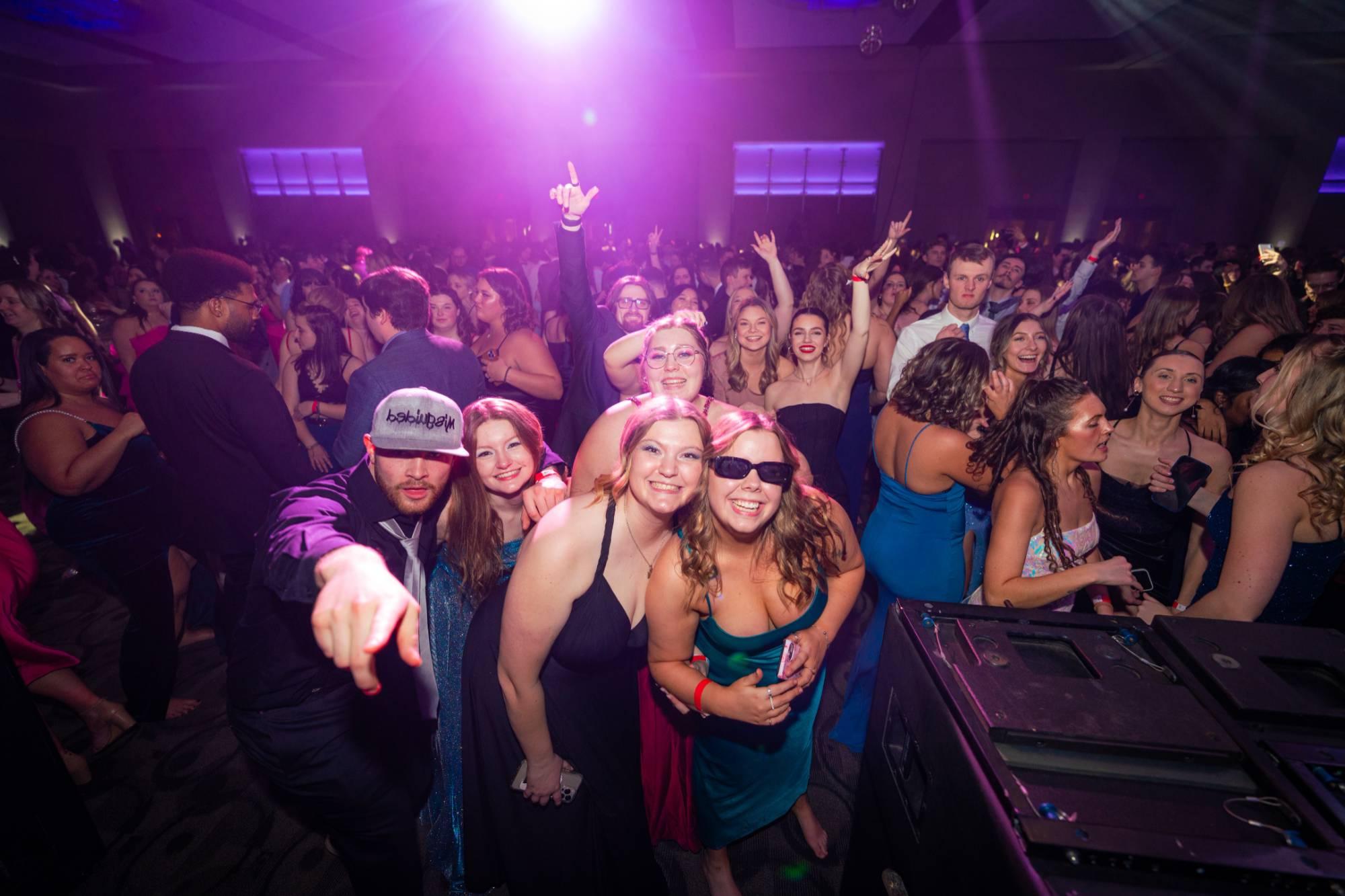 Students dancing, smiling, and pointing at the camera at Presidents' Ball